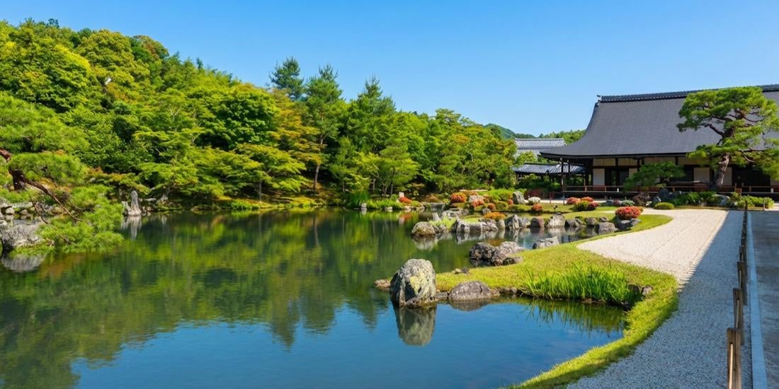 Jardin Sogenchi au temple Tenryu-ji à Kyoto avec étang paisible, rochers et pavillon traditionnel japonais entouré de verdure