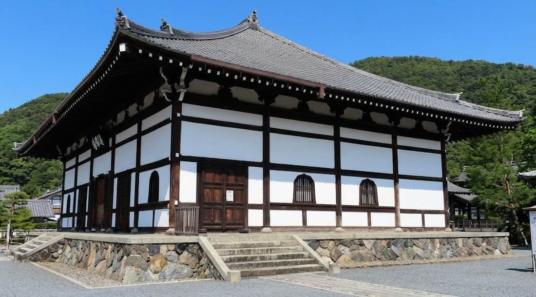 Vue extérieure du hall d'enseignement Hatto du temple Tenryū-ji à Kyoto, montrant l'architecture bouddhiste zen traditionnelle avec des murs blancs, des boiseries sombres et un toit en tuiles sous un ciel bleu.