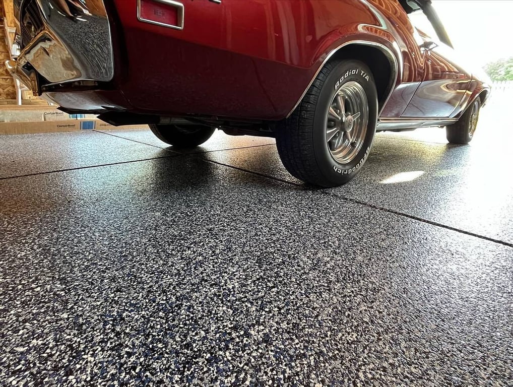 Black, gray and white flake epoxy garage floor under a classic car