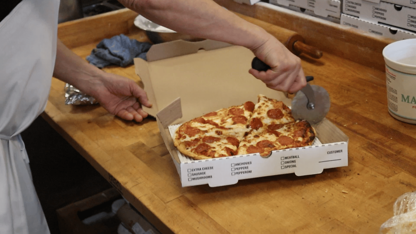 Fresh pepperoni pizza being boxed for takeout at Fournos Pizzeria and Bistro in San Leandro
