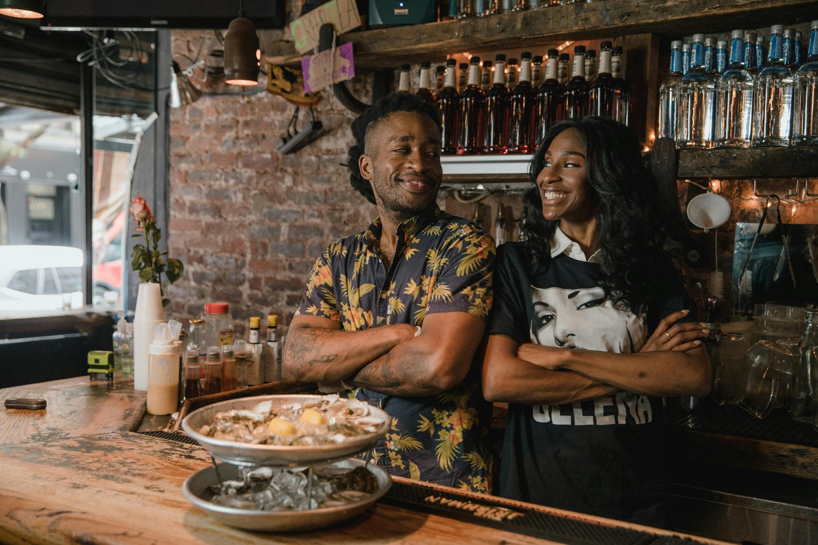 Two restaurant owners standing confidently behind the bar after streamlining operations to reduce service interruptions