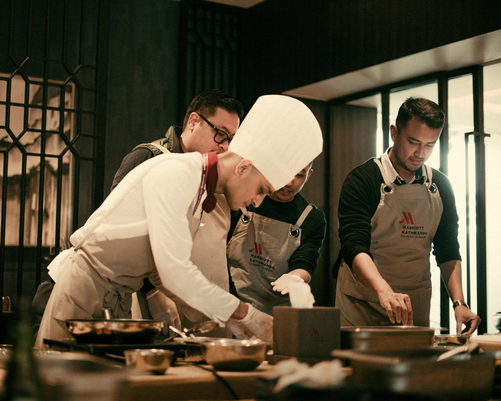 Executive chef coaching back-of-house cooks on prep techniques and station mise en place during a kitchen training session