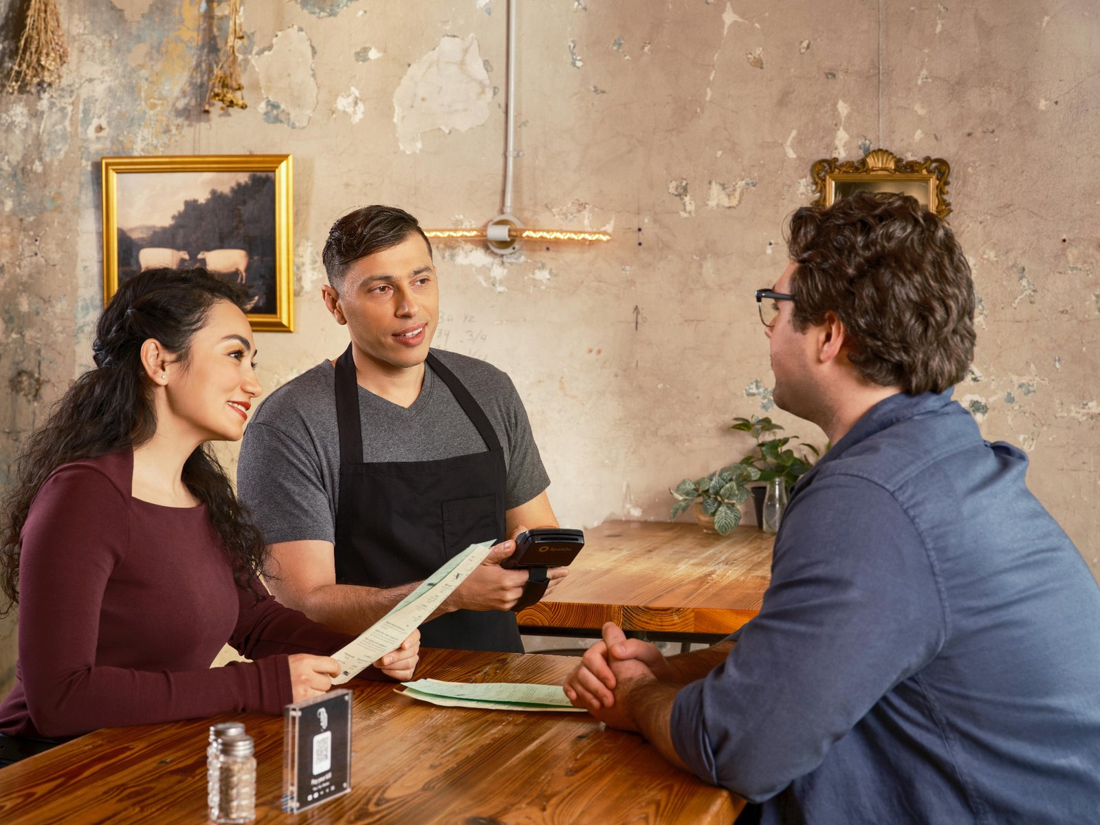 Server using a handheld POS device tableside, showing how voice AI orders sync directly into restaurant point-of-sale systems.