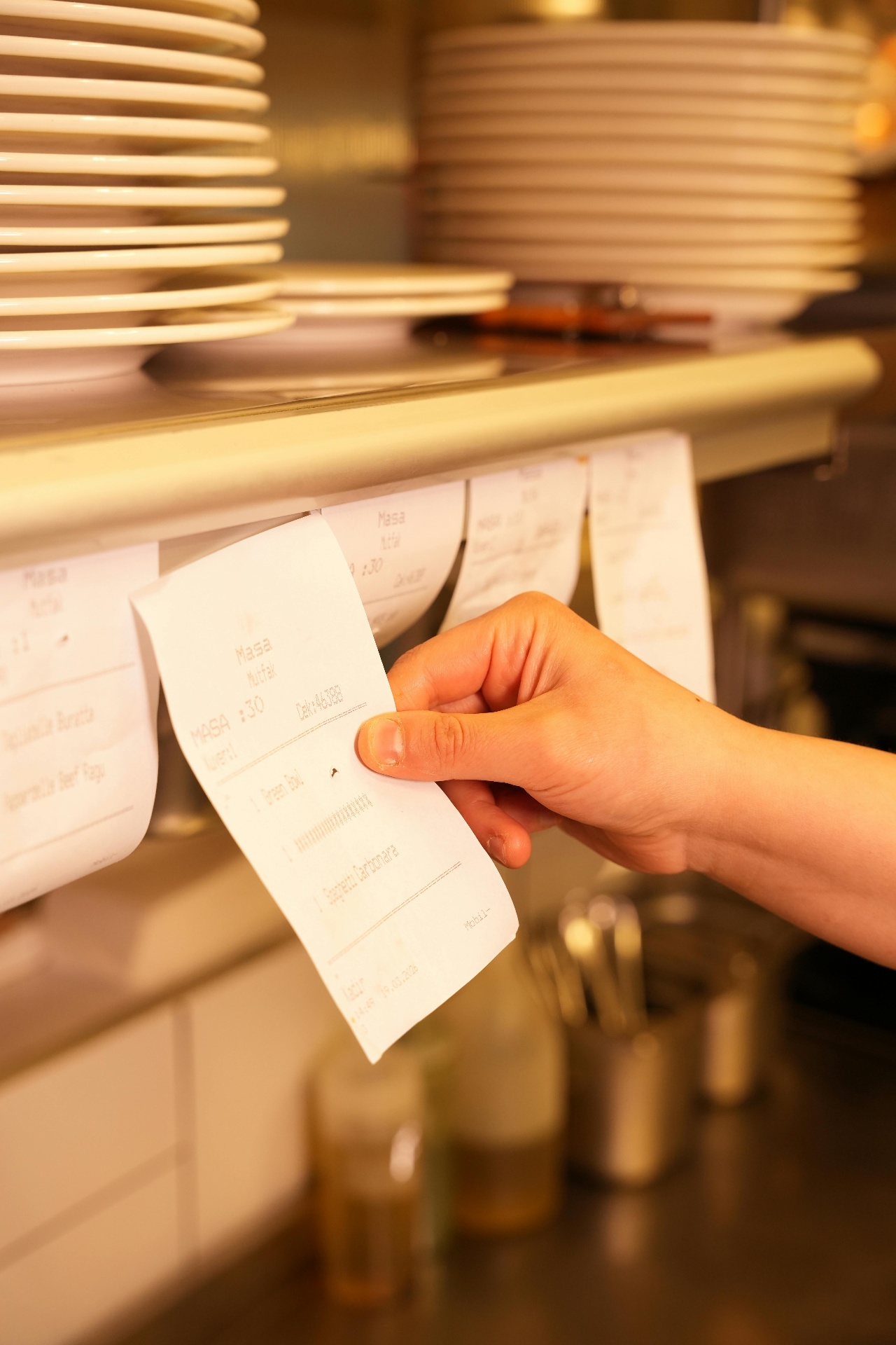 Kitchen line pulling printed order tickets during the dinner rush, illustrating phone order volume restaurants need to manage.