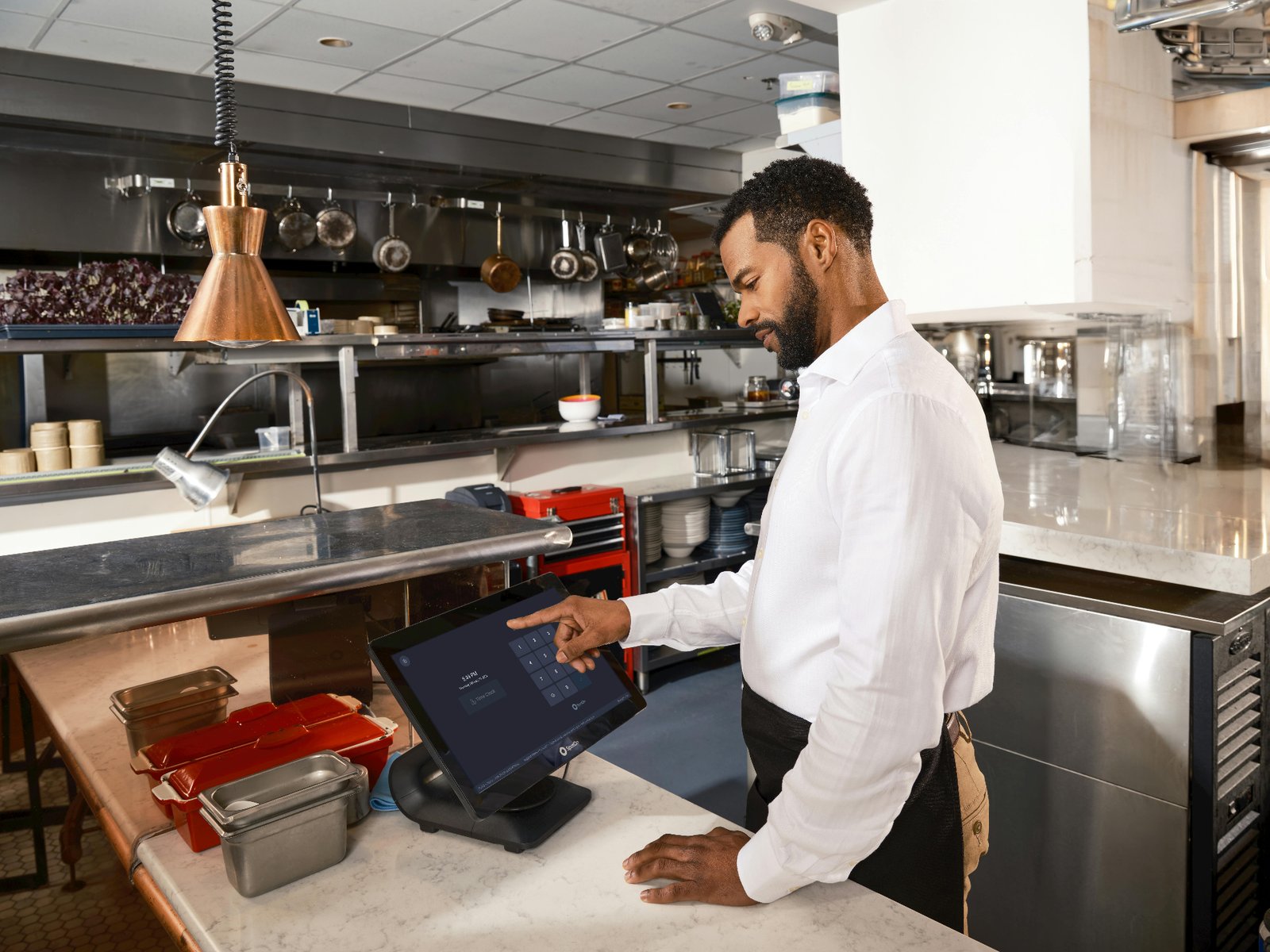 Restaurant manager entering a guest order into a POS terminal to capture customer data at the point of sale