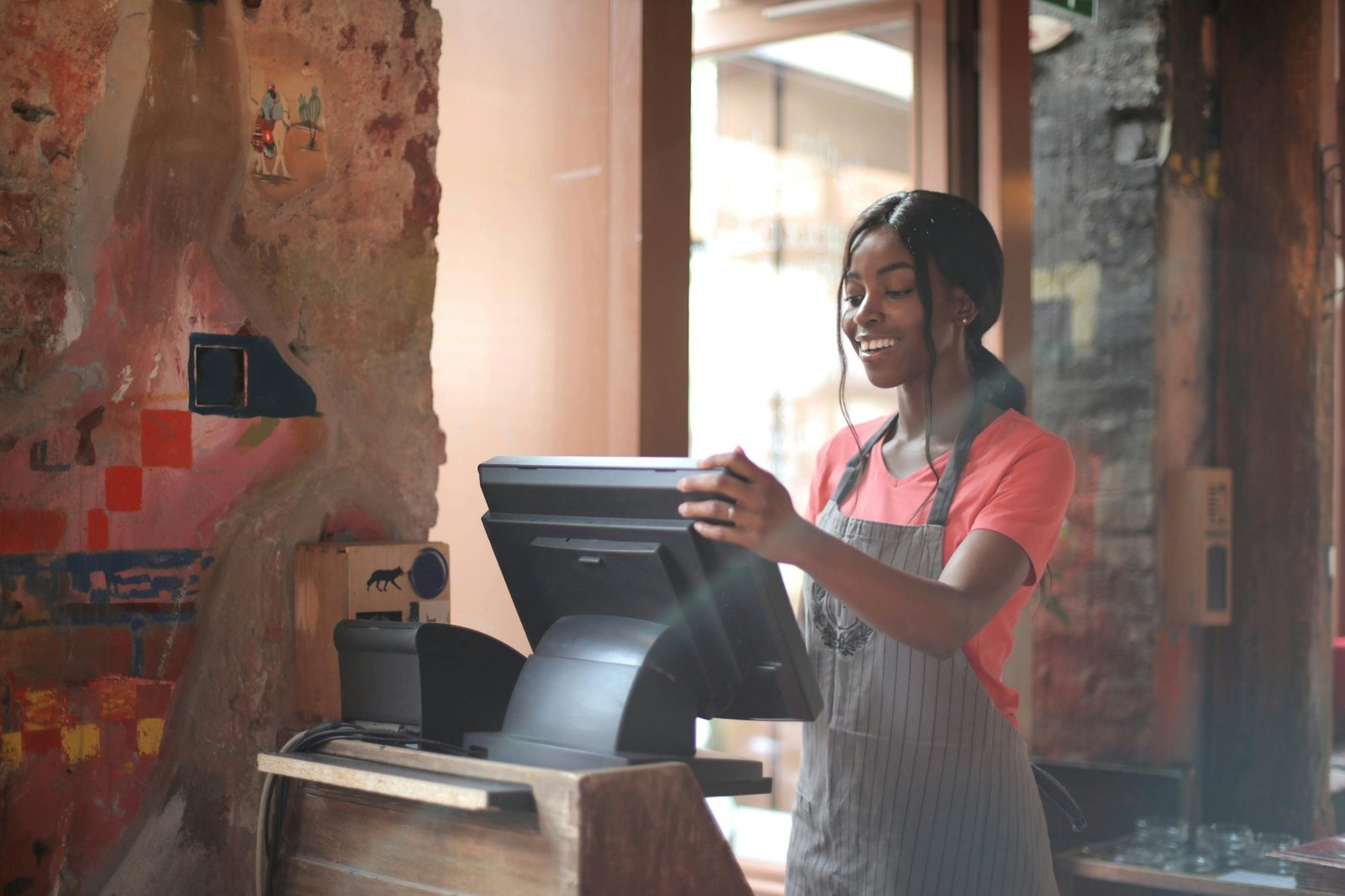 Smiling restaurant staff member working at a point-of-sale terminal