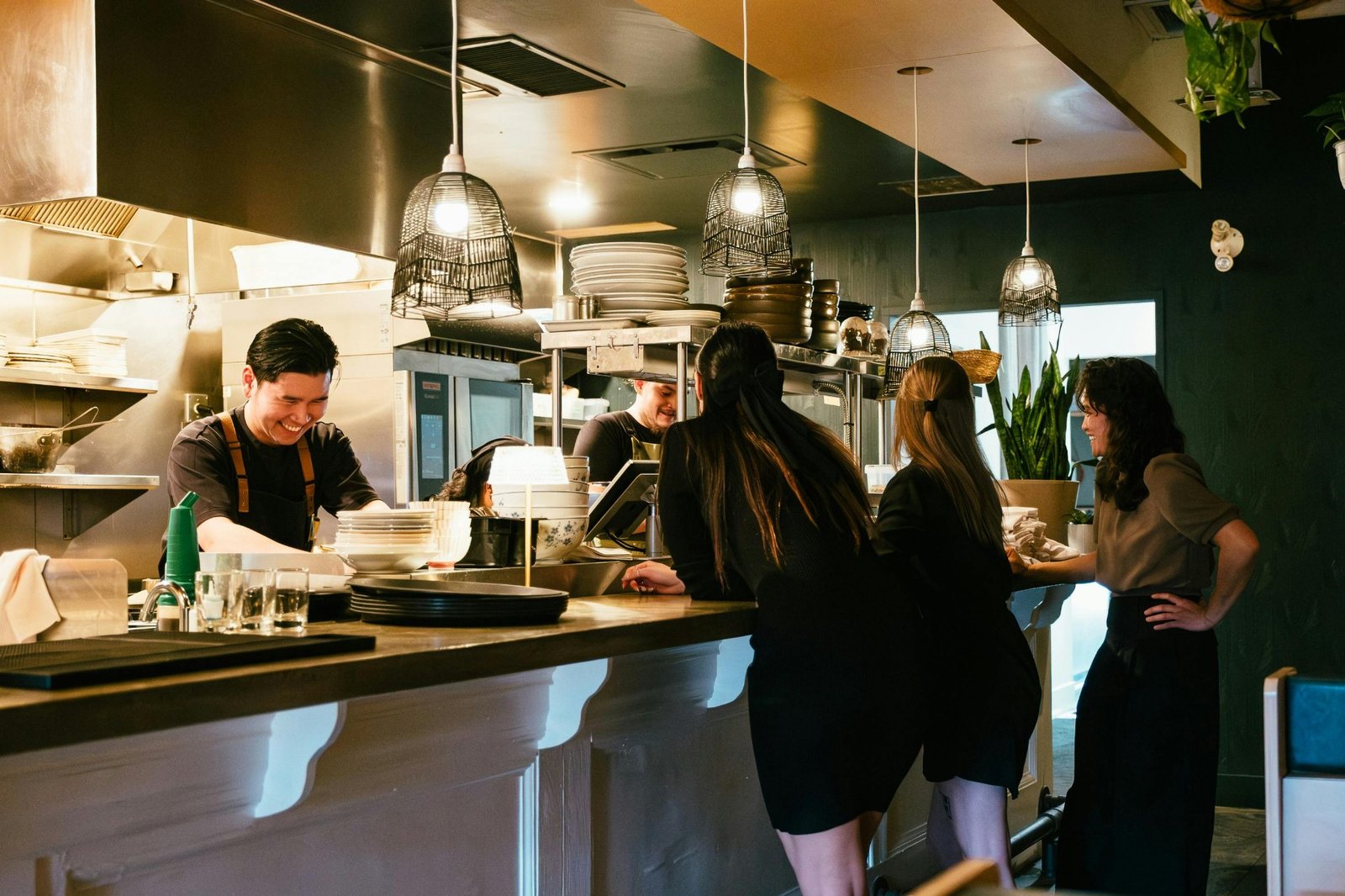 Customers ordering at a modern restaurant open kitchen counter with POS terminal and staff