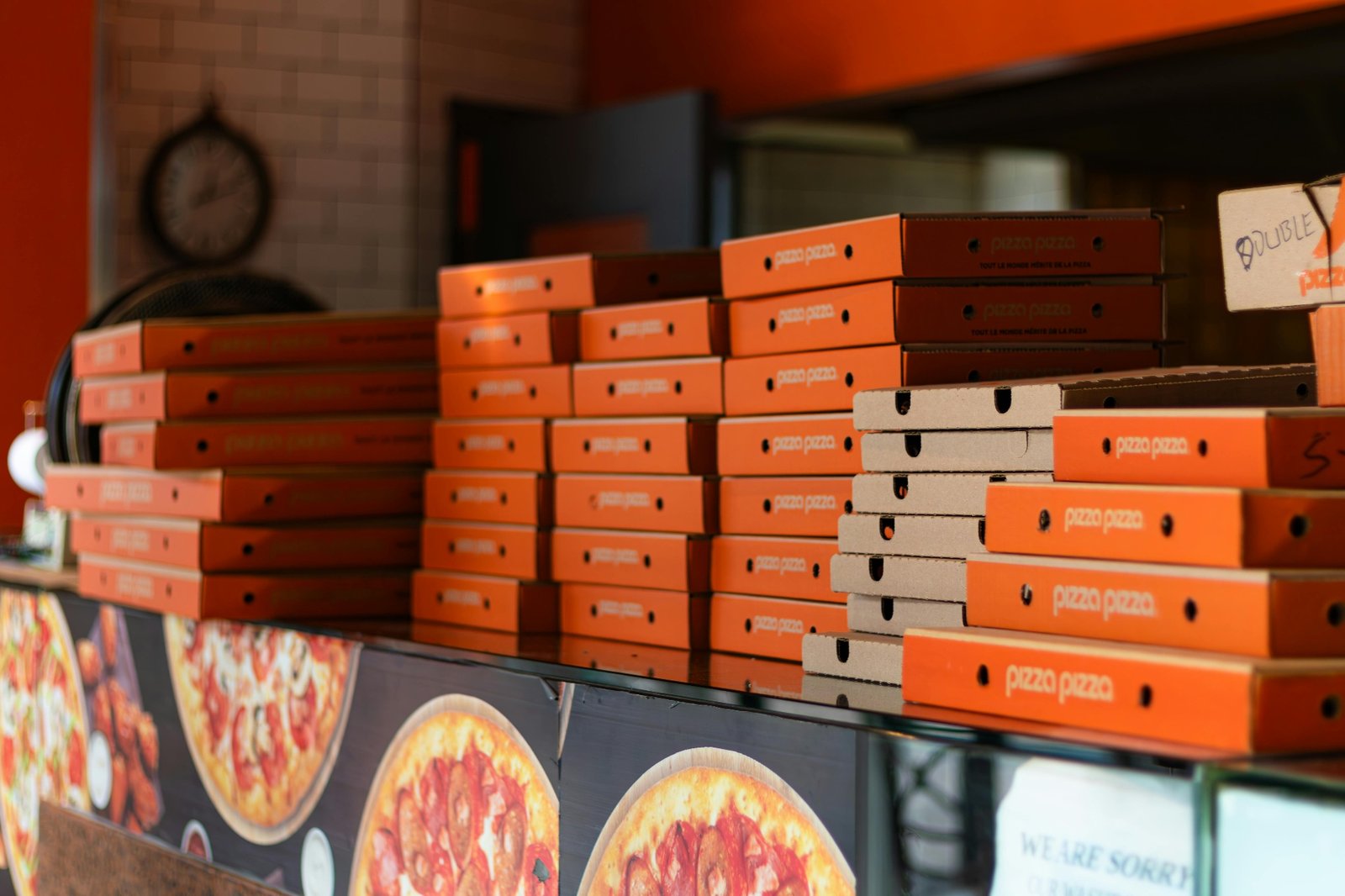 Stacks of branded pizza delivery boxes piled high on the counter during a busy dinner rush