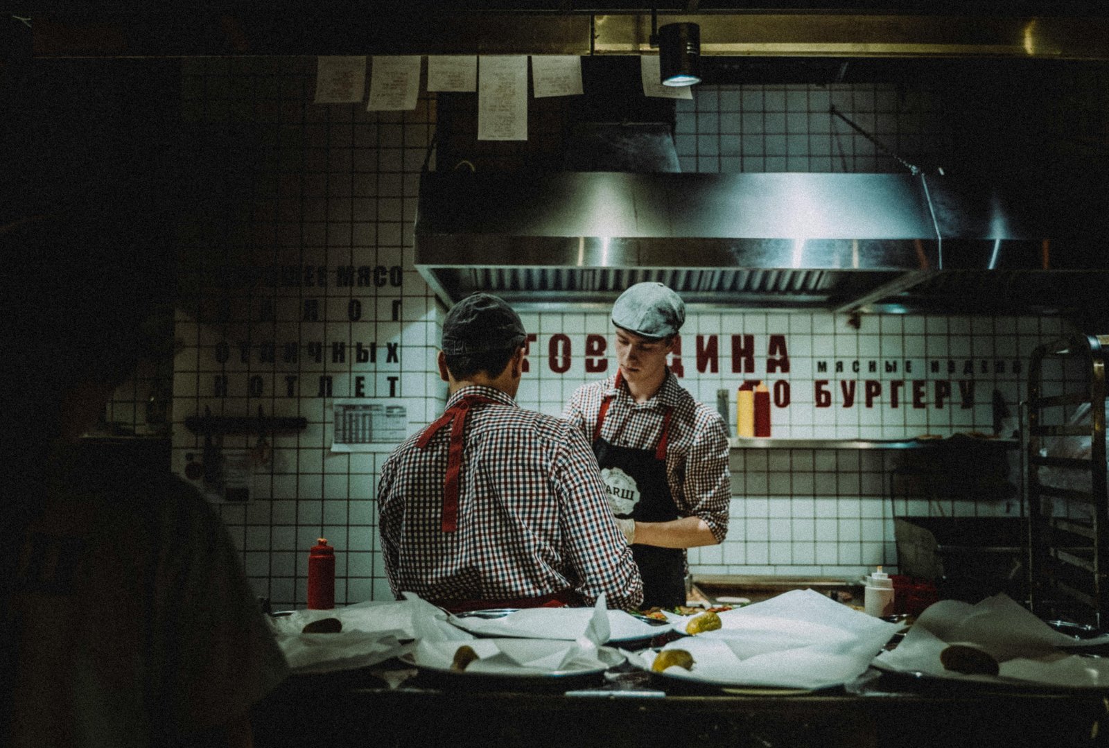 Line cooks preparing burgers in a busy restaurant kitchen