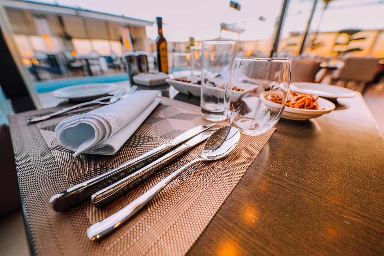 Polished restaurant table set with glassware and cutlery at golden hour