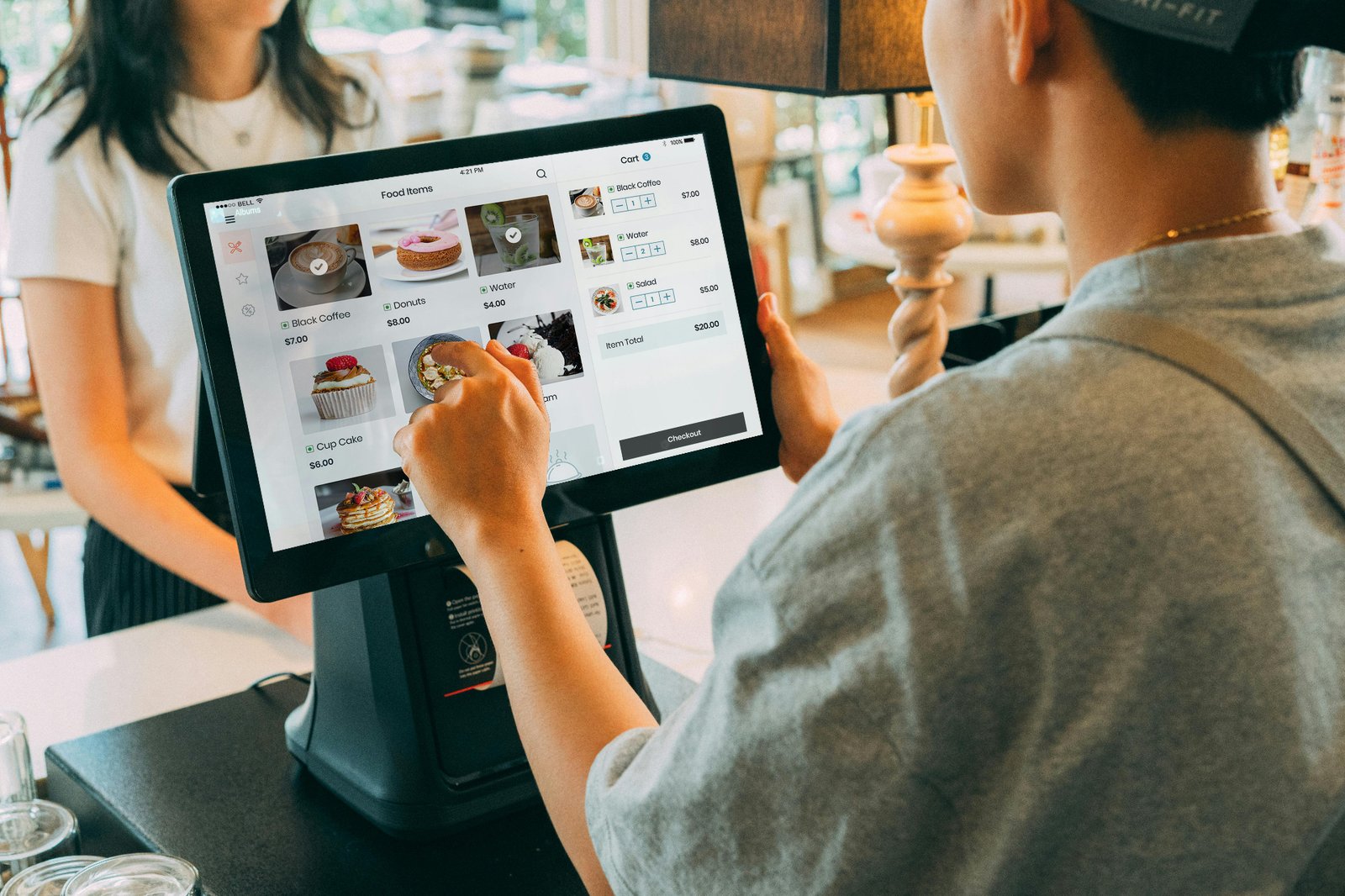 Restaurant guest tapping a smartphone to make a contactless mobile wallet payment at the counter, illustrating modern restaurant payment technology.