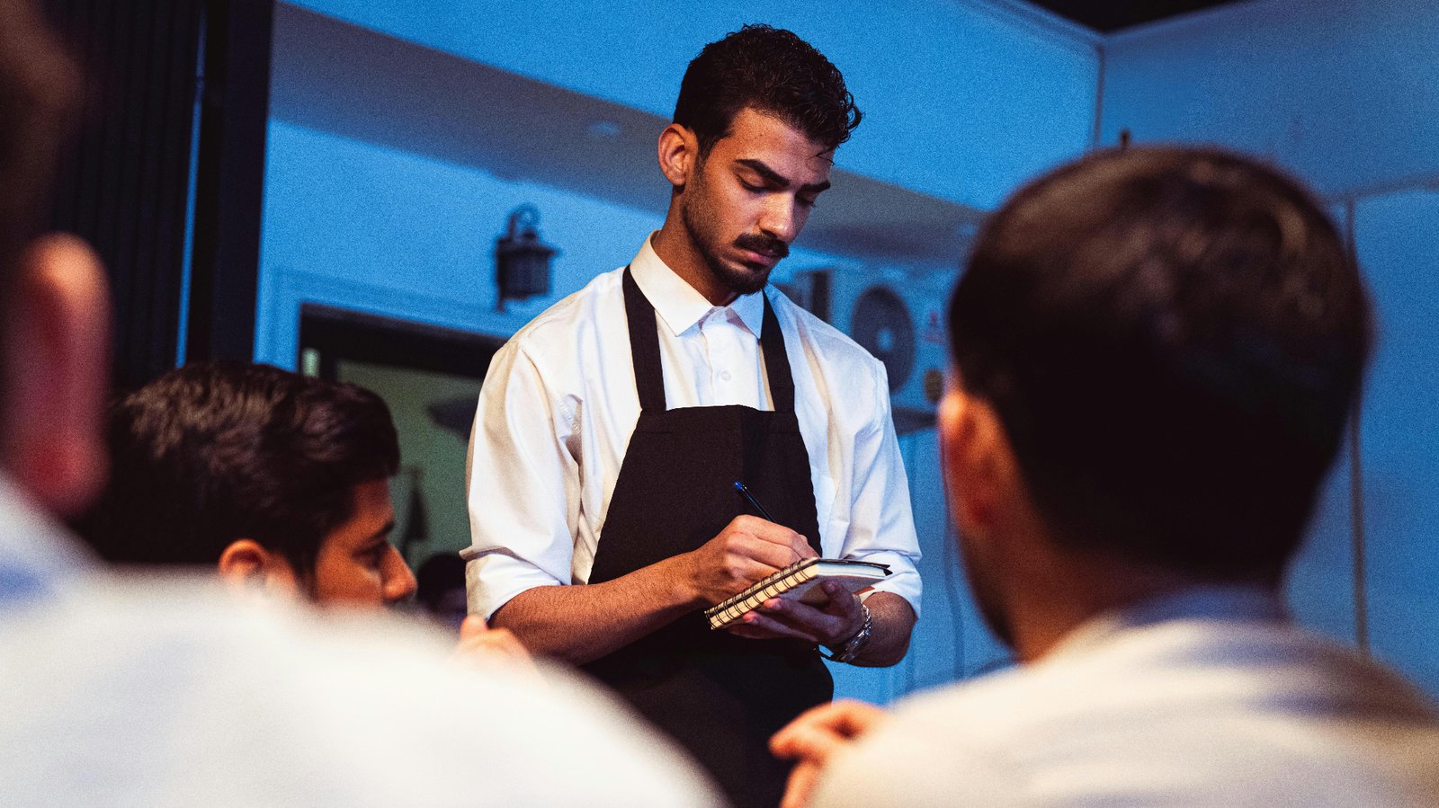 Waiter taking an order on a notepad at a dimly lit restaurant