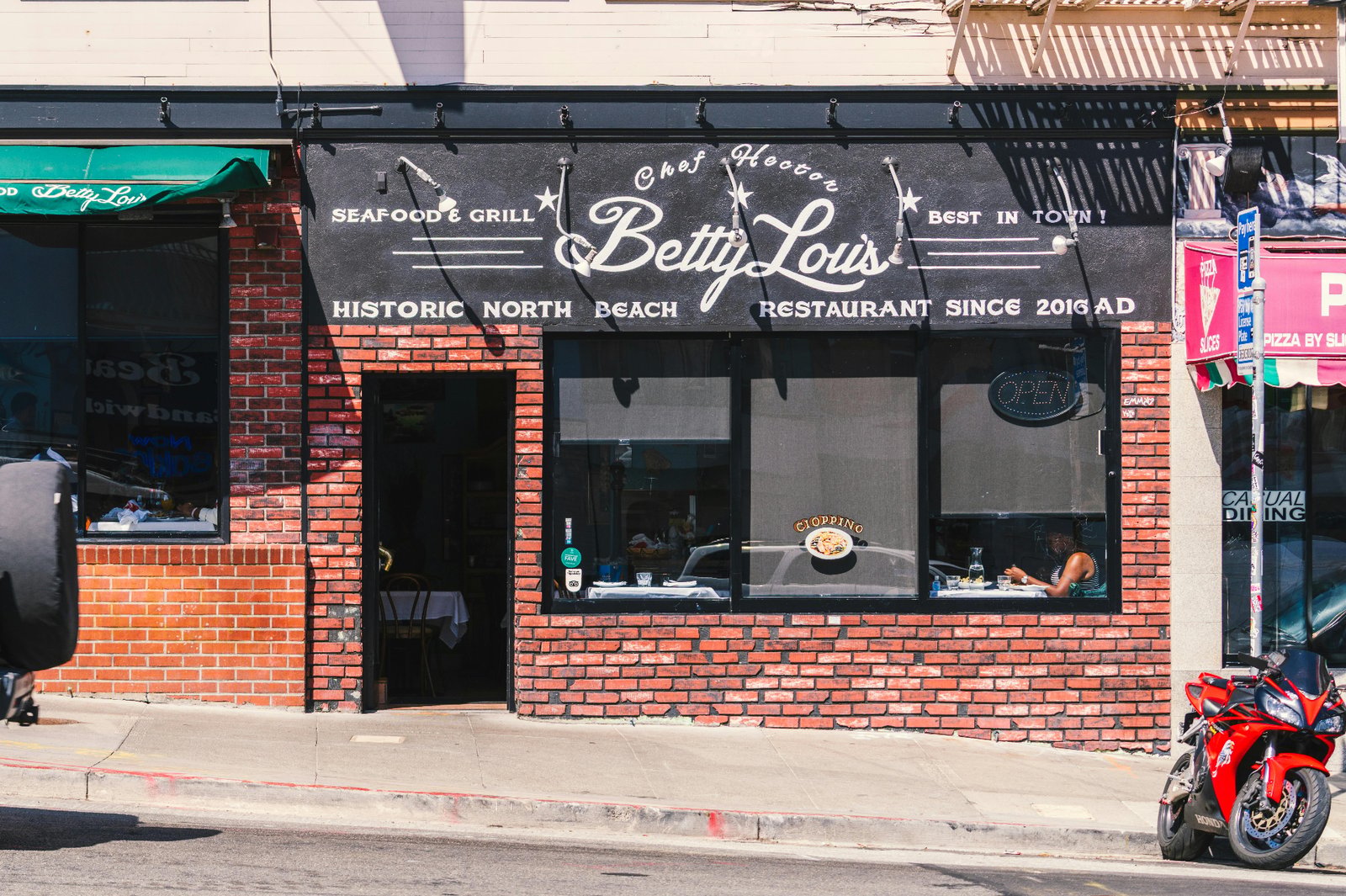 Historic North Beach restaurant storefront with hand-painted signage advertising seafood and grill specialties to local foot traffic