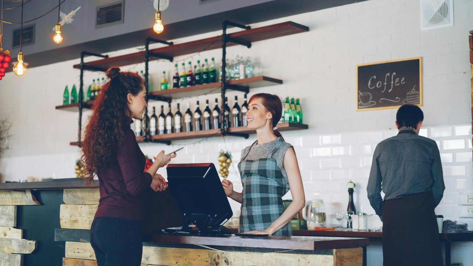 Customer chatting with a friendly cashier at a cafe POS counter