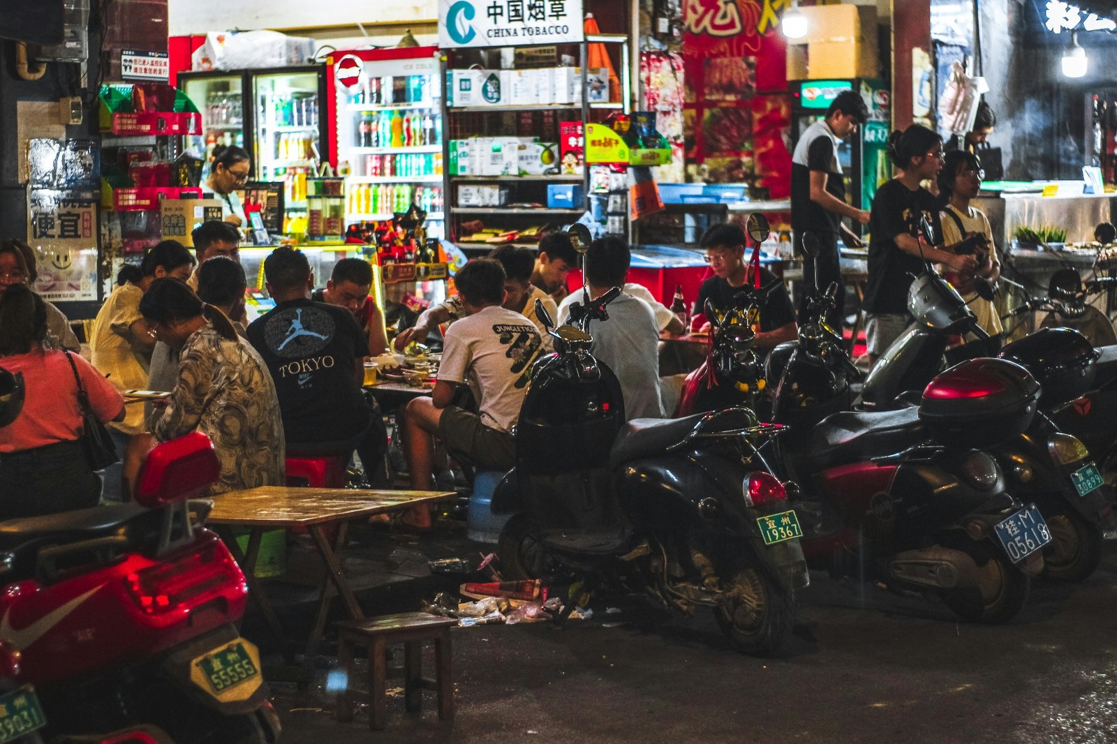 Late-night street food restaurant packed with diners eating at outdoor tables