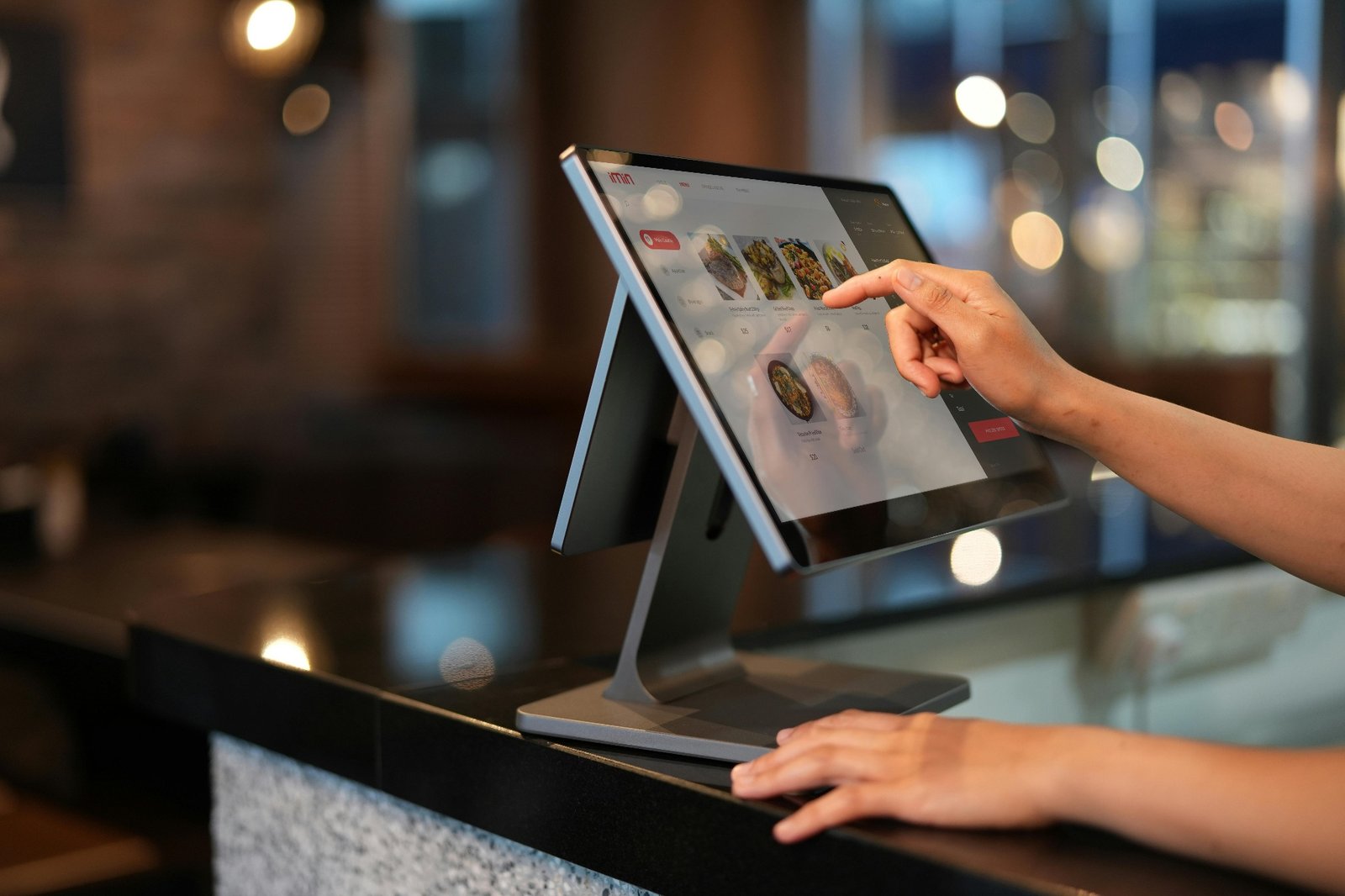 Staff member tapping menu items on a modern touchscreen POS terminal