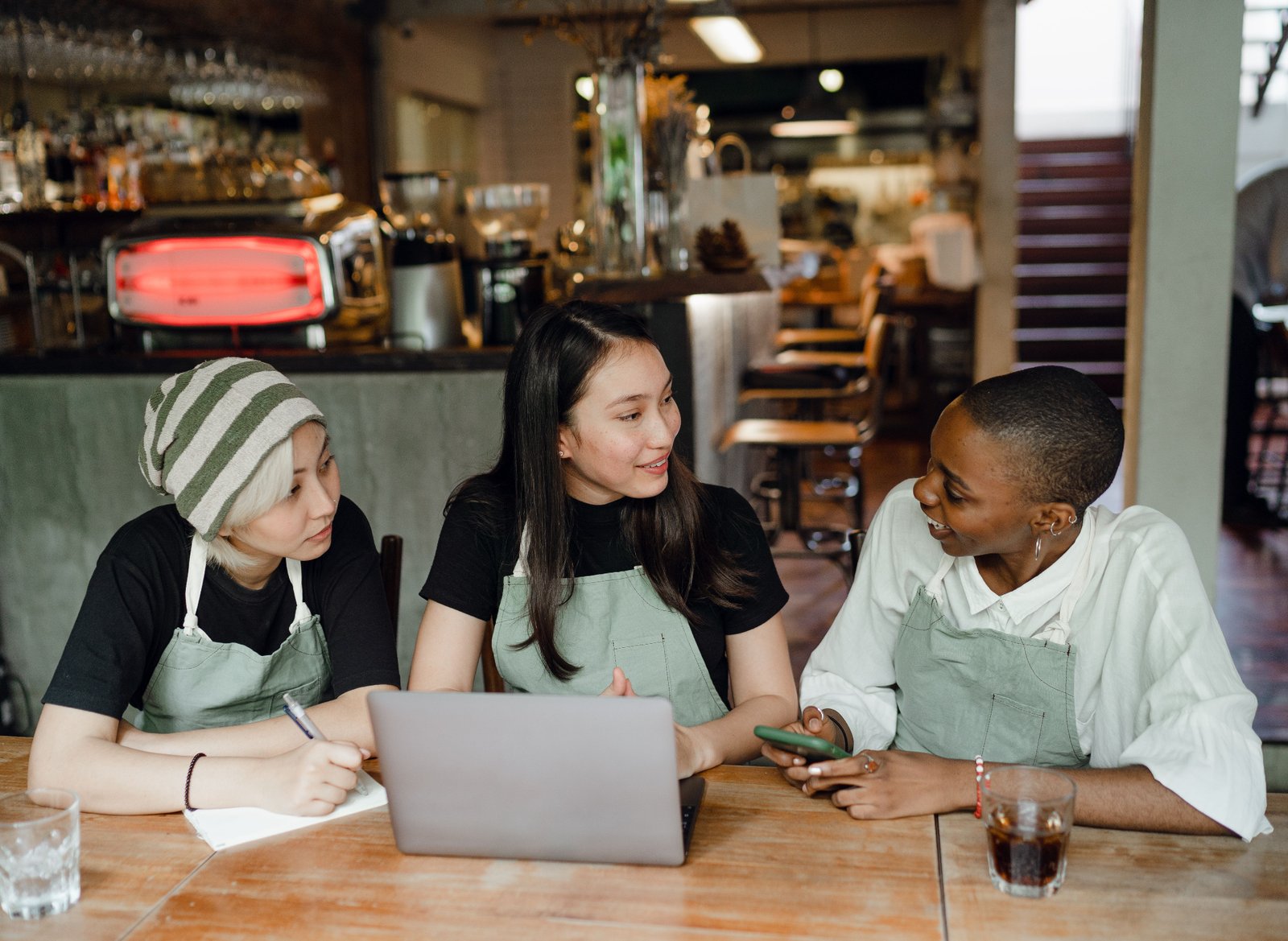 Restaurant manager leading a staff meeting with team members reviewing schedules on a laptop