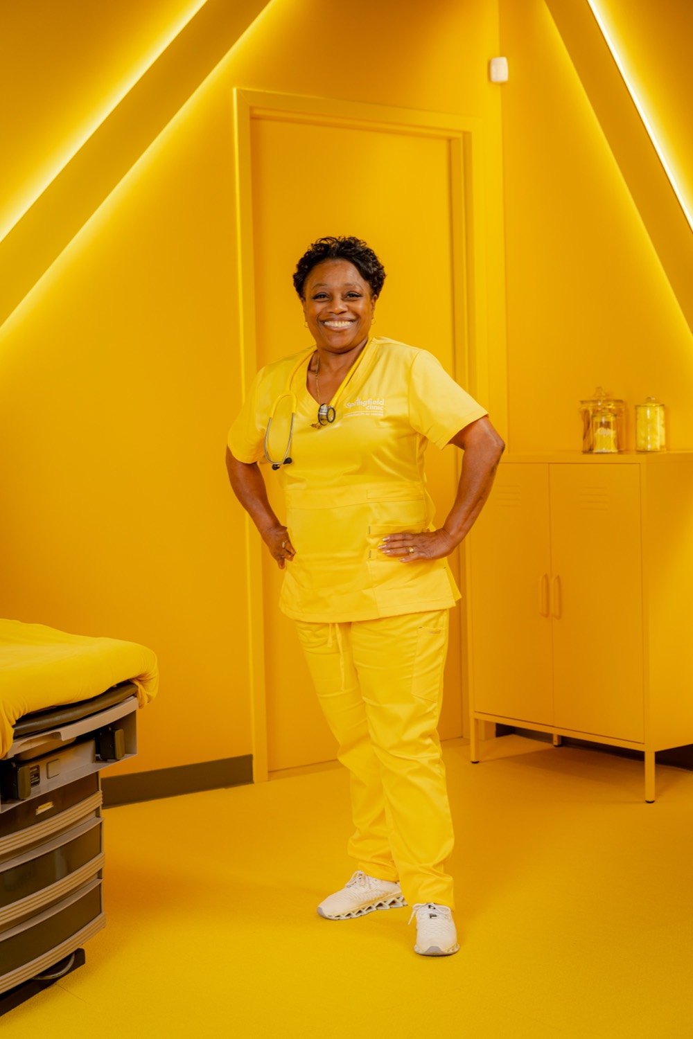 A Springfield Clinic team member smiling in an all-yellow exam room
