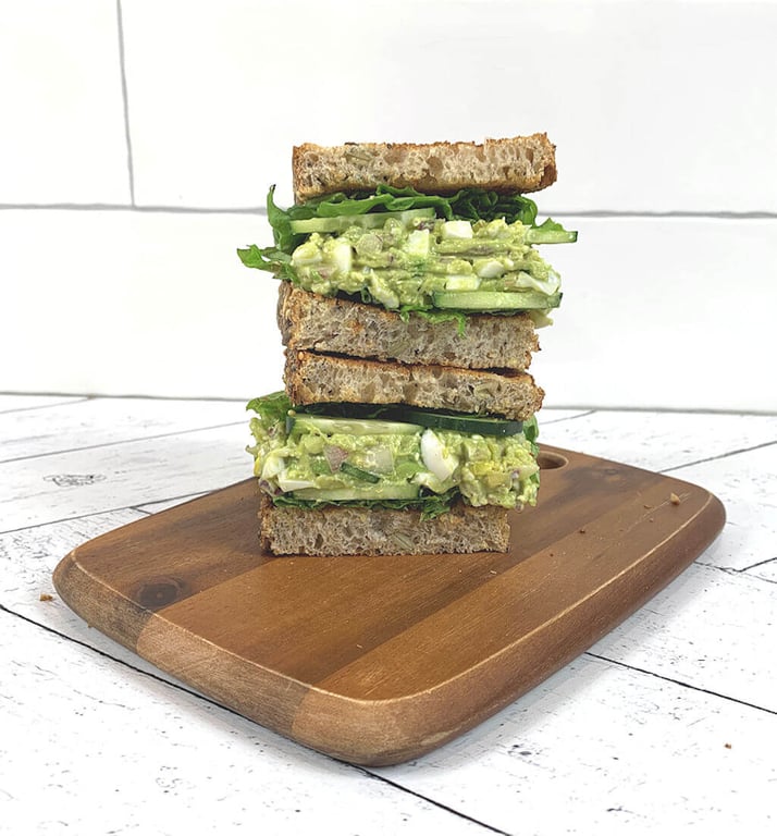 Image of 2 half avocado egg salad sandwiches on top of each other.