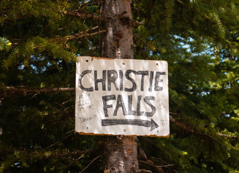 Sign that says "Christie Falls" in the trees.