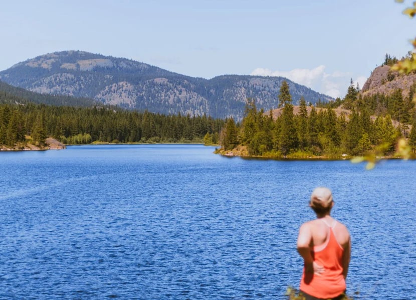 Woman in red stands on the shores of the Rose Valley Reservoir