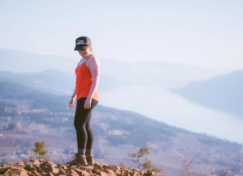 Woman in red standing at the summit of Spion Kop, overrlooking Lake Country and Okanagan lake.