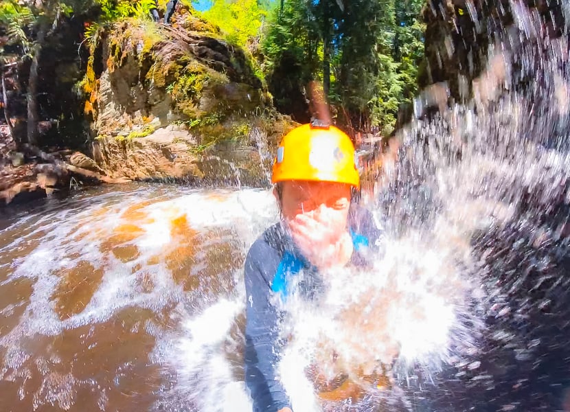 A woman jumps into a creek from the cliff