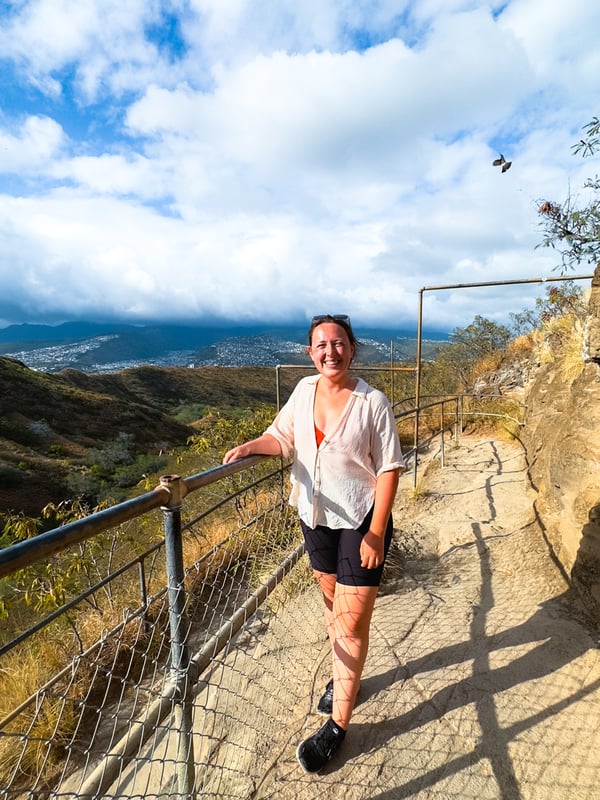 Woman leans against a guardrail on the trail.
