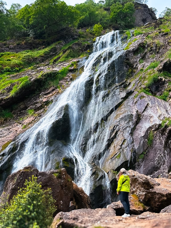 Huge waterfall with a woman standing at the bottom.