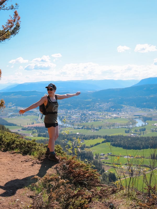 Woman stands on the edge of the Enderby Cliffs Trail and enjoys the view.