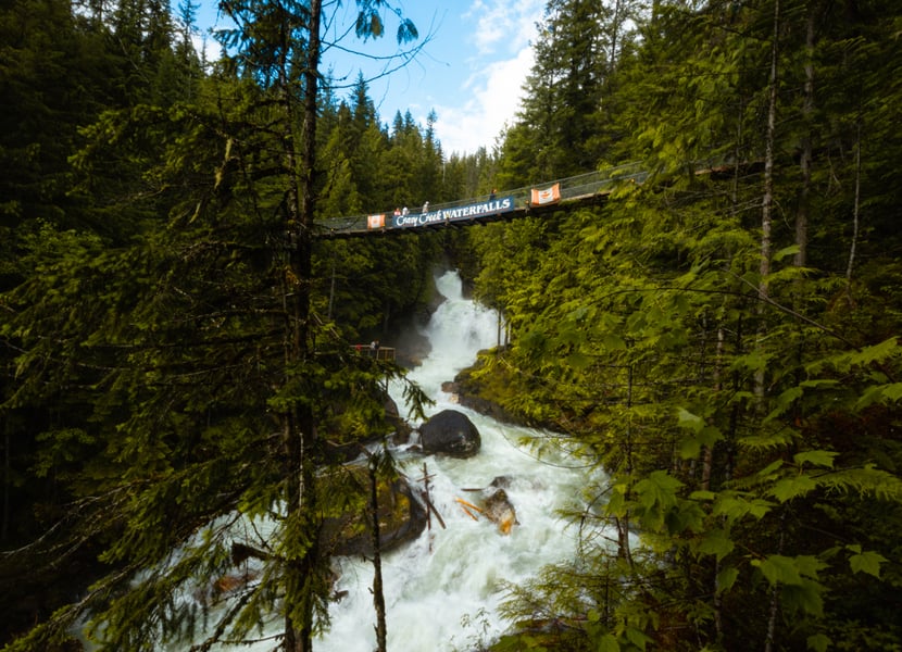 Suspension bridge with the words "Crazy Creek" above a large, roaring waterfall