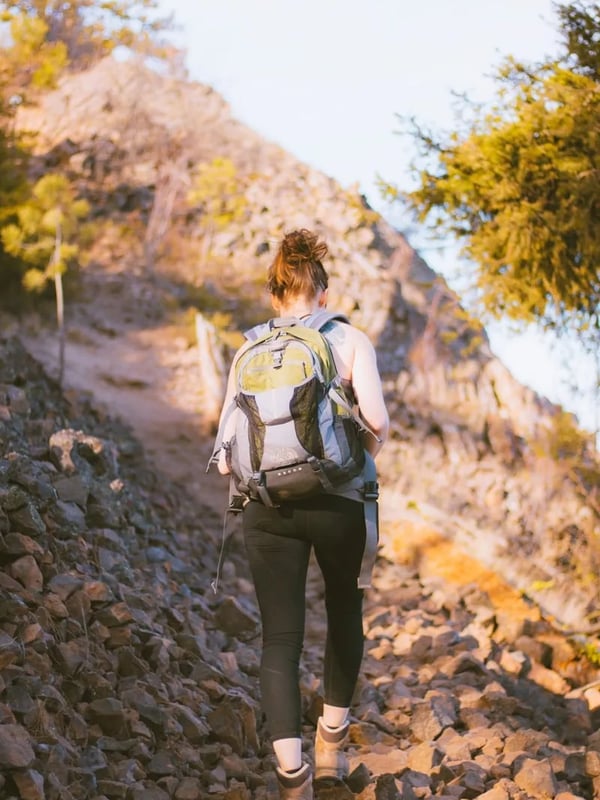 A woman hikes over a field of rocks at Spion Kop.