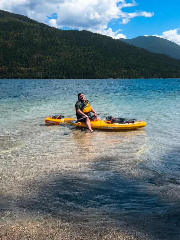 Man sitting on a yellow paddleboard on a blue lake
