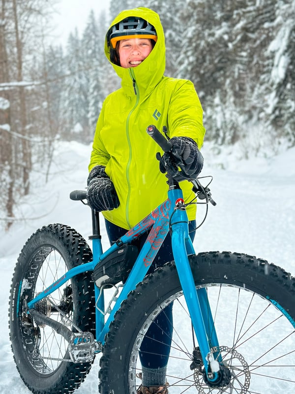 Woman holds a fat bike on a snowy trail