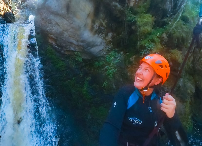 A woman looks back at a waterfall she ziplined down in an Okanagan canyon