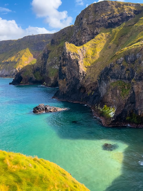 The turquoise ocean and green cliffsides at Carrick-a-Rede Rope Bridge in Northern Ireland