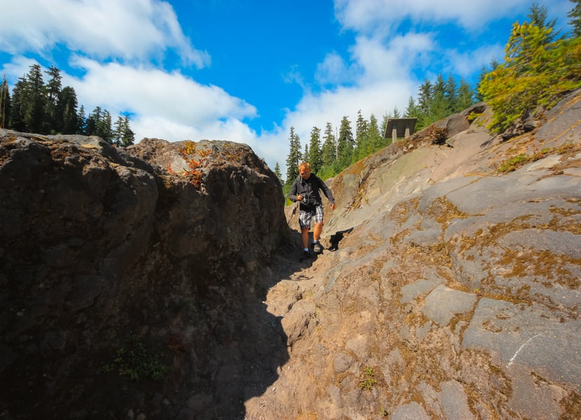 Man walking through a narrow rock passage along the Lava Canyon Trail near Mount St. Helens