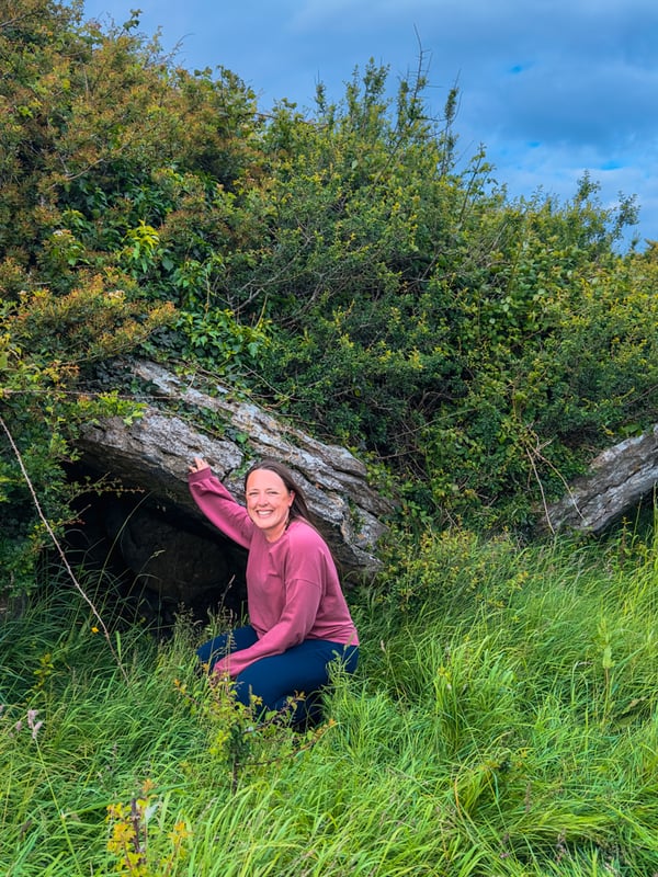 Woman standing in front of a collapsed portal tomb.