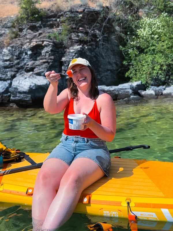 Woman sitting on a paddleboard eating watermelon