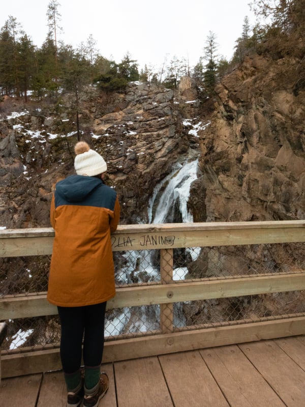 Woman looks at a frozen waterfall