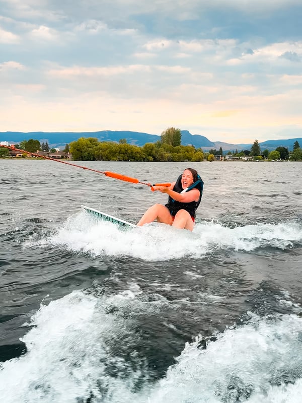 Woman struggling to get up on a wakeboard.