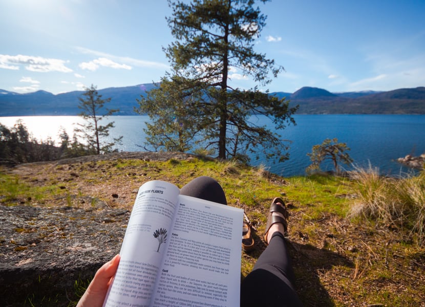 Woman reads a book with views of Okanagan Lake in Ellison Provincial Park