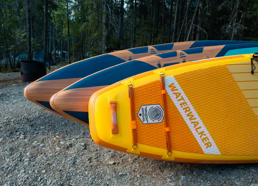 Three paddleboards lined up beside each other, with a yellow "Waterwalker" at the front
