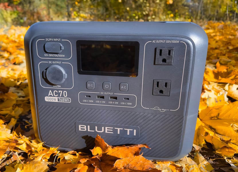 Bluetti AC70 1000W power station sitting in a bed of leaves.