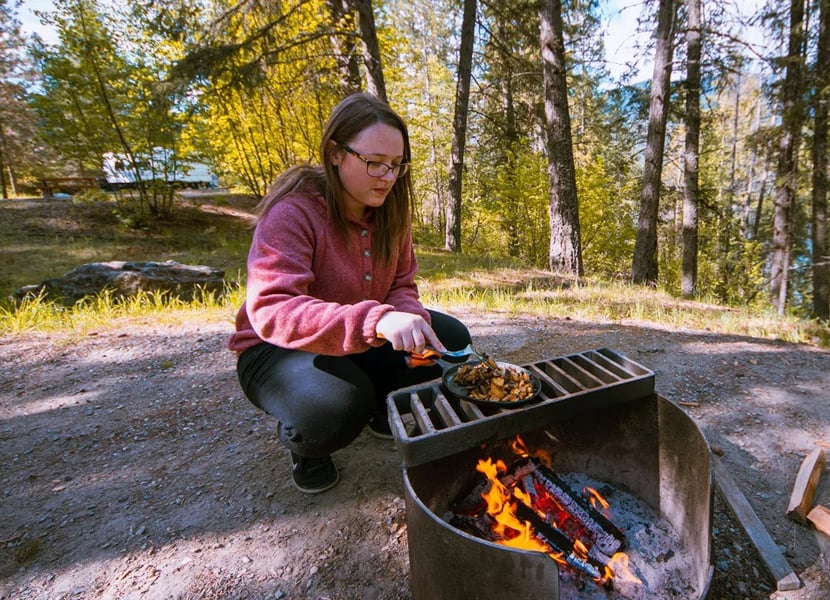 Woman cooks on a firepit at a campsite at Texas Creek campground