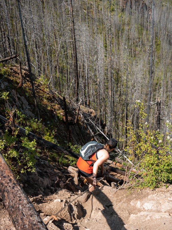 Woman scrambles down the steep trail to Christie Falls with the help of a rope.