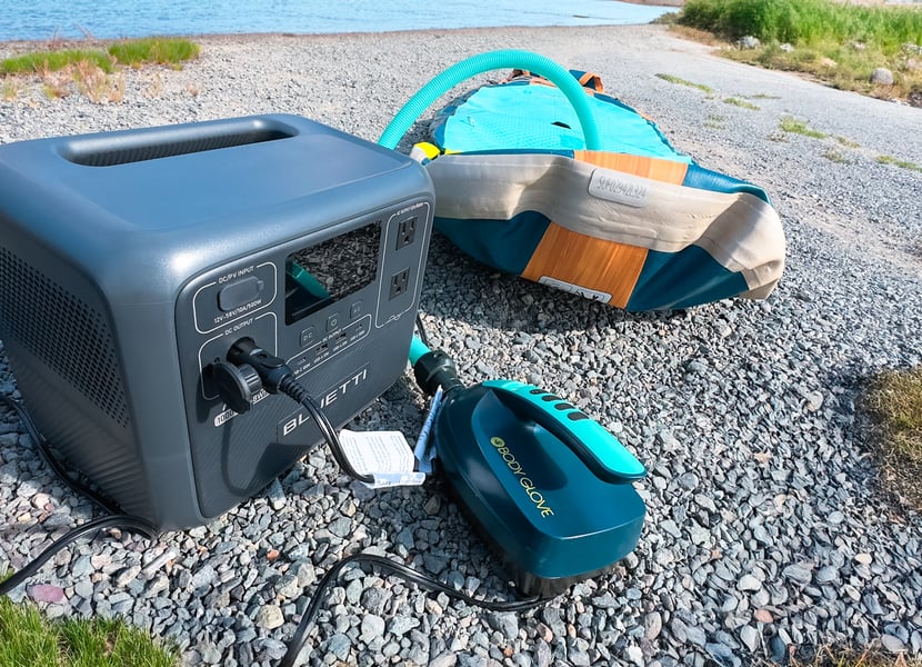 Bluetti AC70 powering a paddleboard pump and blowing up a paddleboard on the edge of a lake.