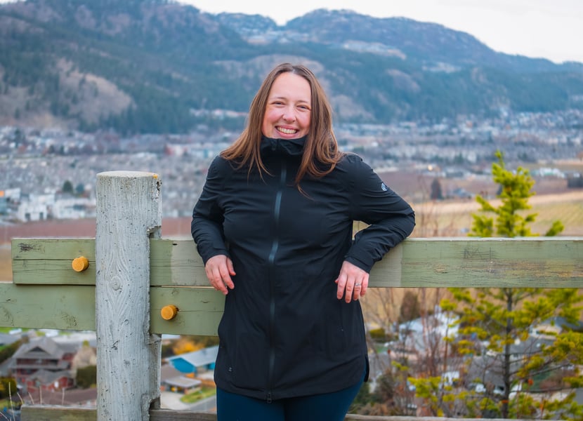 Woman leaning against a wooden fence.
