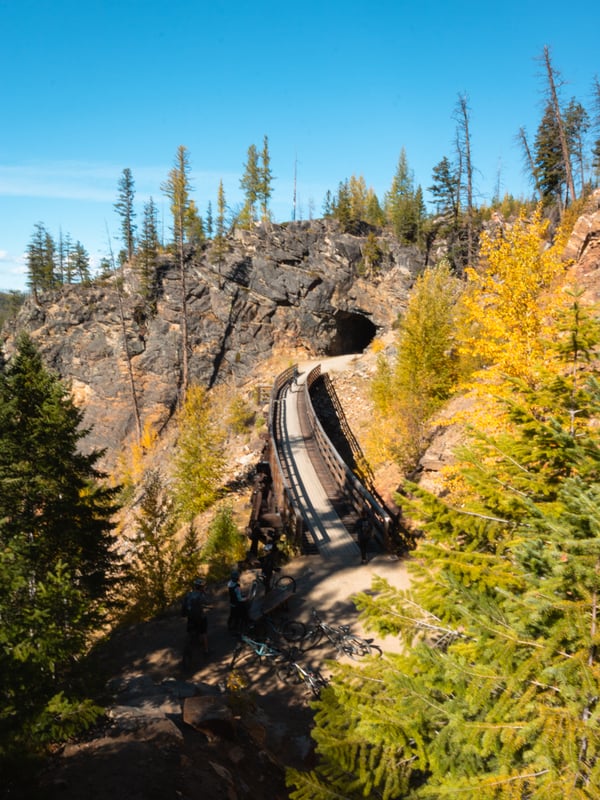 A historic, wooden trestle heading into a dark tunnel at Myra Canyon in Kelowna BC