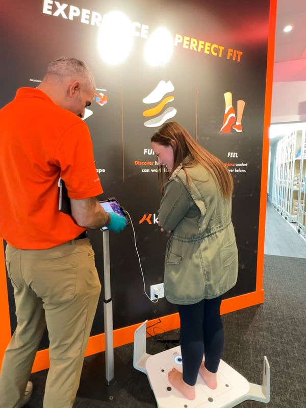 Woman stands on a 3D foot scanner.